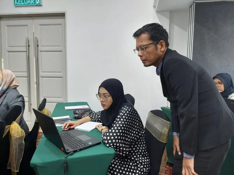 Coach Adi Zain helping a participant with a laptop activity
